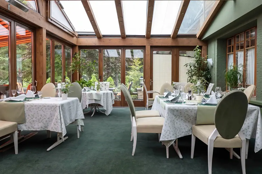 Wintergarten mit Glasdach und gedeckten Tischen