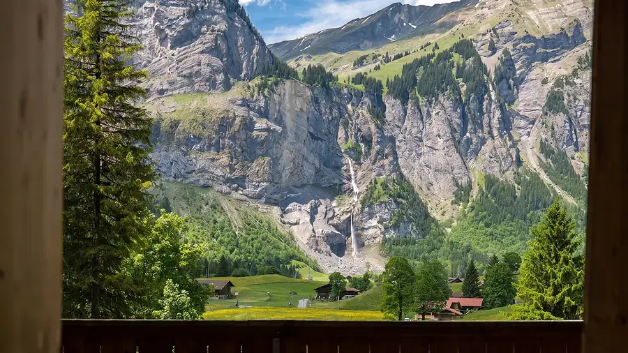 Aussicht vom Balkon auf Fels, Wasserfall und Wiesen